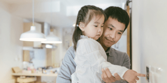 Father helping daughter adjust thermostat
